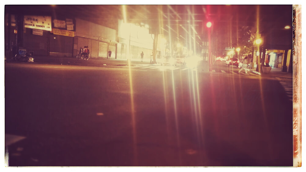 an edited photo titled 'Fordham Glow', from the City Slick collection of JTJ' White's City Series photography. The image is a photograph of the corner of Jerome Avenue and Fordham Road in The Bronx