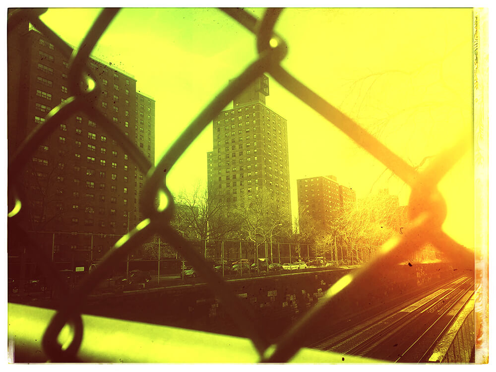 an edited photo titled 'Misty Morris', from the City Slick collection of JTJ' White's City Series photography album. This photograph is of a building in Morris Houses projects in The Bronx edited with an orange-yellow hue effect